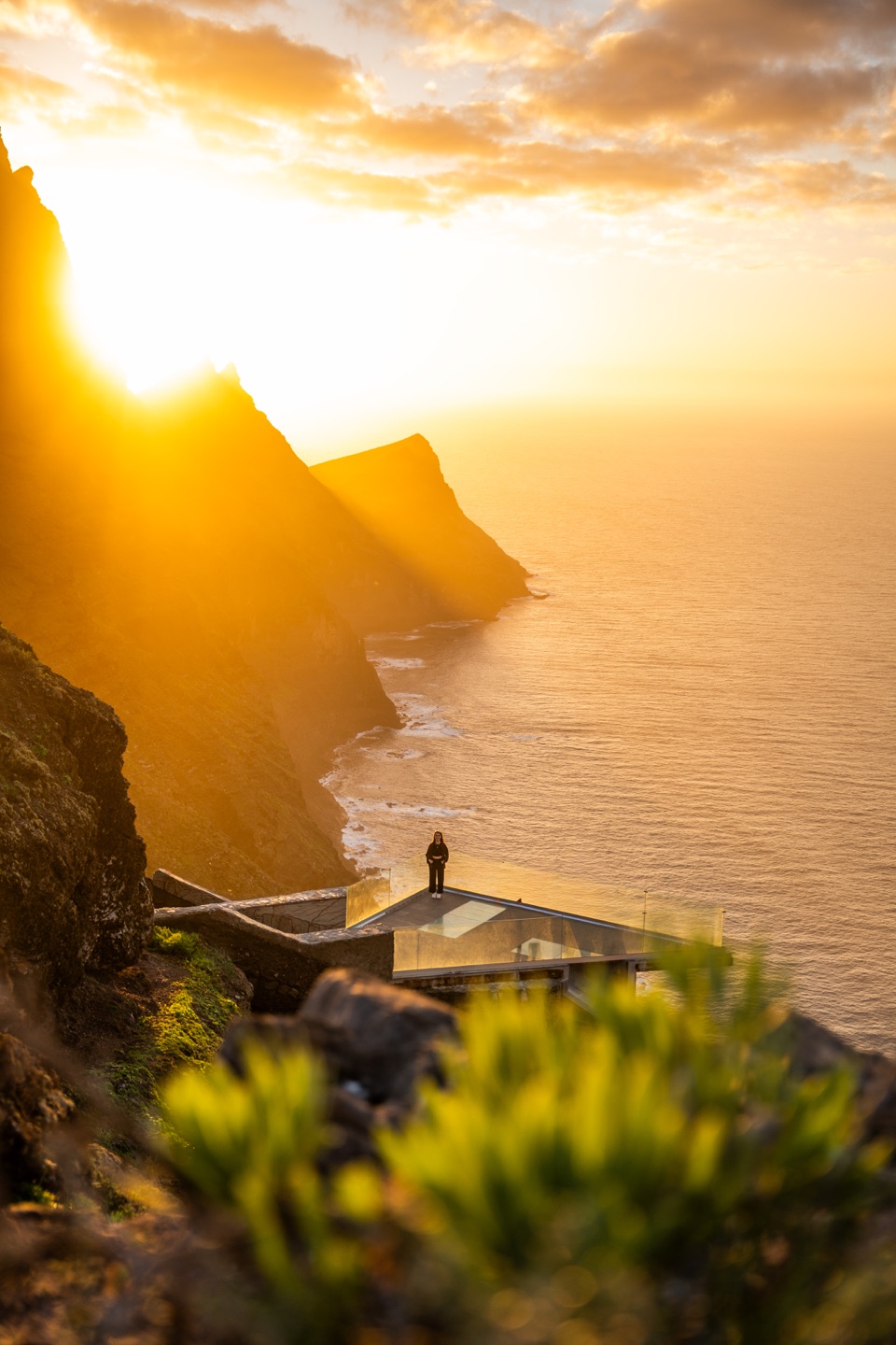Person an einem Aussichtspunkt über einer Steilküste im goldenen Sonnenlicht